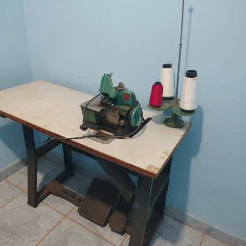 Máquina de costura do tipo overlock, montada em uma bancada de trabalho própria, 250 reais