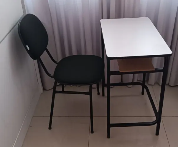 Mesa com porta livro e cadeira de secretária. 