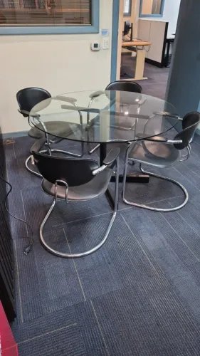 1 mesa com tampo de vidro com pé preto, medindo1,0 de diâmetro e 4 cadeiras em couro preto