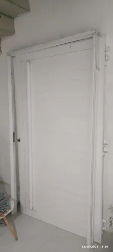 Porta pivotante em alumínio branco com frisos horizontais e puxador vertical 