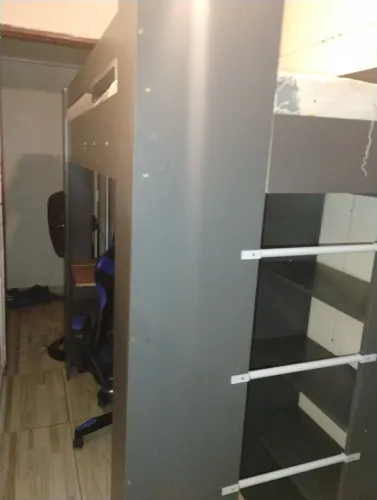 Cama de solteiro com mesa de computador e prateleiras embaixo.