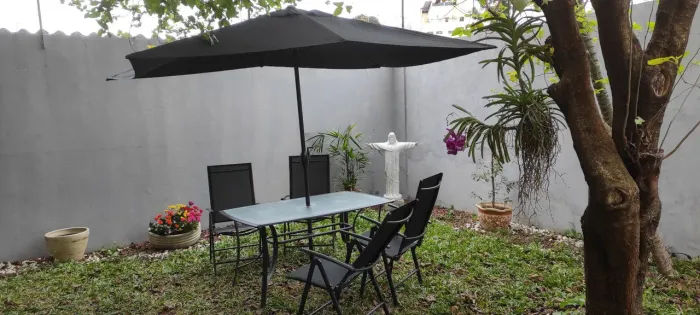 Mesa externa com ombrelone e lugares