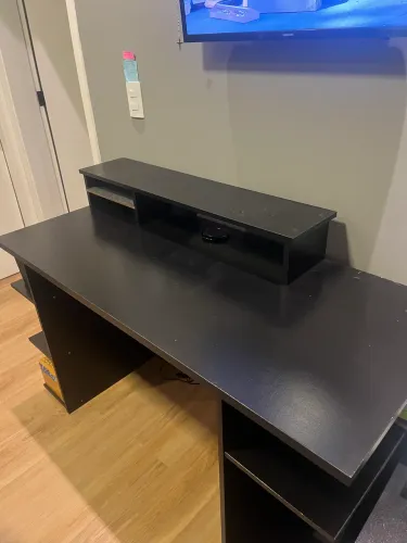 Mesa para escritório preta com alguns detalhes de uso