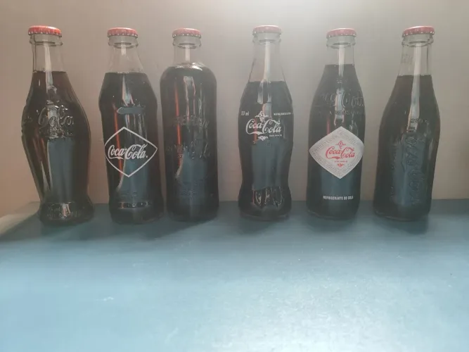 Coleção da evolução das garrafas da coca cola