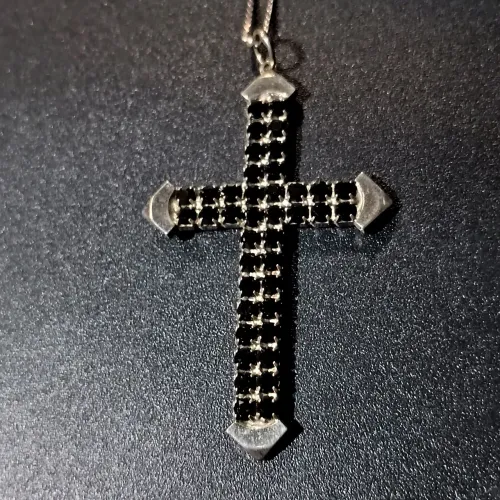 Corrente de prata acompanhando com uma cruz com detalhes em preto e pontas em prata