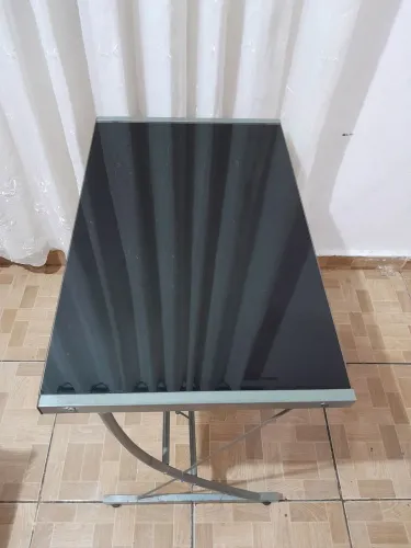 Mesa de escritório de vidro e cadeira estofada.