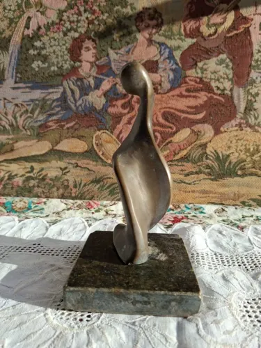  escultura abstrata que lembra uma figura humana estilizada, em bronze com base de mármore