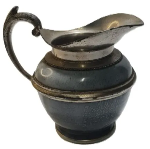 Jarra antiga, possivelmente um cremeiro ou jarra de agua feita de metal com um acabamento 