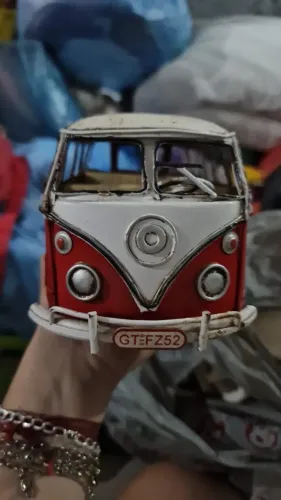 Miniatura é uma Kombi de metal vermelha e branca com estilo vintage rústico.