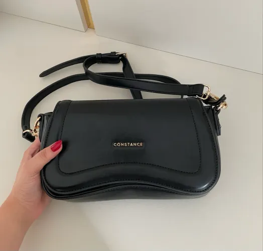 Bolsa Constance preta, com zíper e alça regulável. Seminova