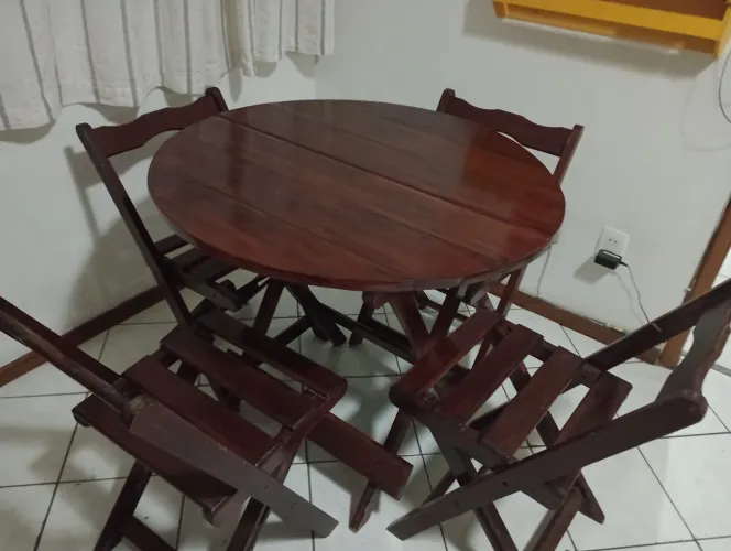 Mesa dobrável com quatro cadeiras de madeira.