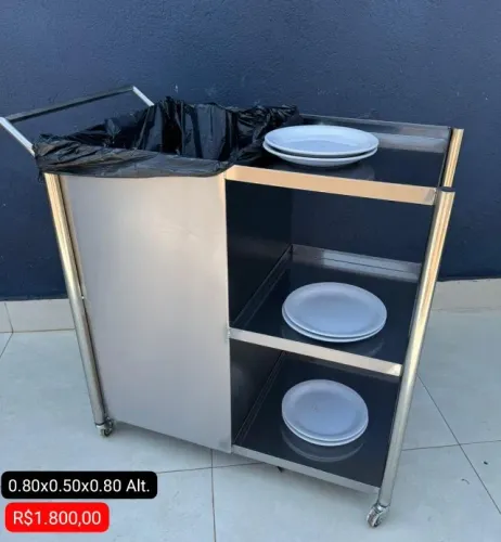 Carrinho inox com lixeira e prateleiras.
