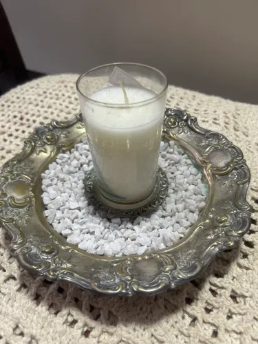 Bela composição de castiçais com um copo de cristal, pedrinhas brancas.