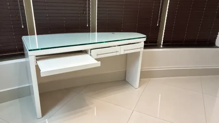 Mesa branca com tampo de vidro, gavetas e bandeja retrátil