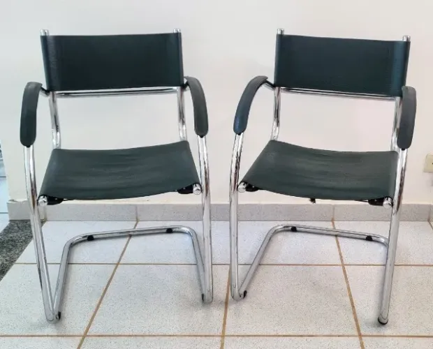 Duas cadeiras interlocutor, de estrutura cromada, sem riscos, com revestimento em couro