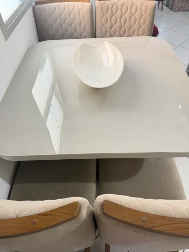 Mesa em tampo de vidro off white com 4 cadeiras acolchoadas.