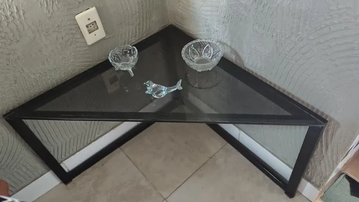 Mesa de canto em formato triangular em metal laqueado preto, tampo em vidro fumê.