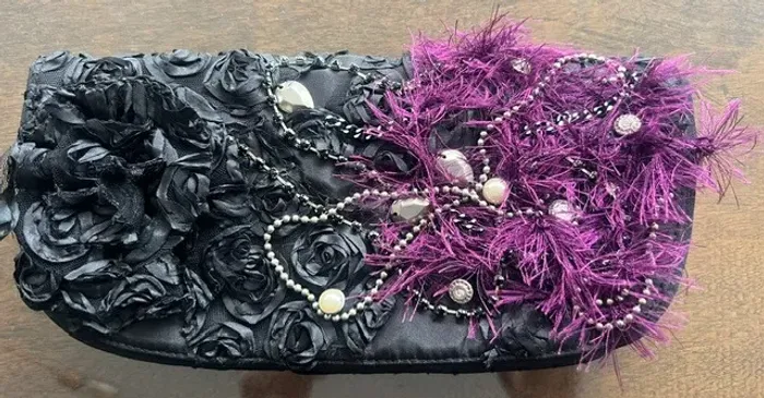 Clutch preta artesanal decorada com flores em tecido e fios vinho.