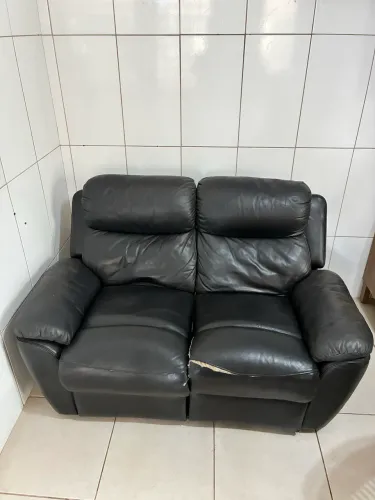 Sofá reclinável de 2 lugares em cor preta, revestimento em couro e suportes para os pés
