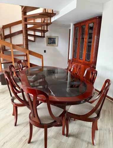 Sala de jantar com cadeiras e cristaleira .