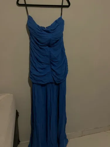 Um elegante vestido longo azul tomara que caia com drapeado na parte superior.