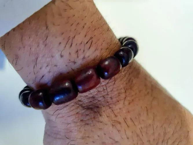 Pulseira feita com contas de madeira em tom avermelhado escuro