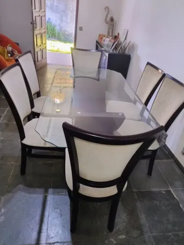 mesa de jantar retangular com tampo de vidro e 6 cadeiras com assento almofadado e encost