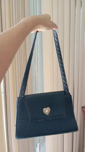 Bolsa preta de mão, com algumas marcas de uso apenas na frente 