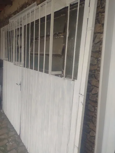Vende se um portão de garagem com porta auxiliar e proteção de grade 
