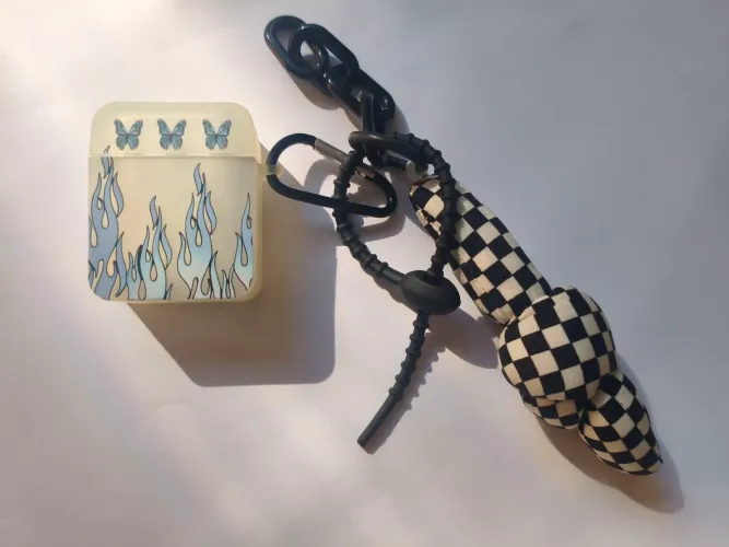 Capinha para fone bluetooth na embalagem com chaveiro e adereços.