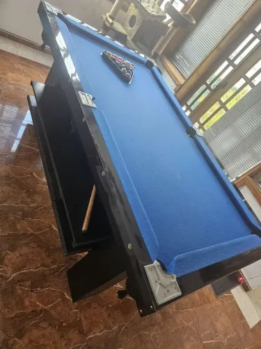 Mesa de bilhar com tacos e bolas