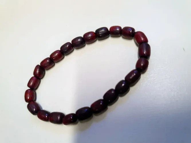 Pulseira feita com contas de madeira em tom avermelhado escuro