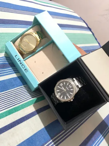 1 relogio orient masculino prata e um relógio lince feminino