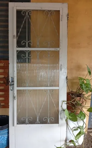 Porta de ferro com grade e vidros s/ marco.
