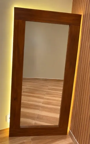 Espelho com moldura artesanal em madeira, acabamento em verniz e iluminação LED indireta.