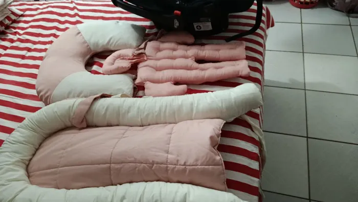 Bebê conforto y ninho com almofada de amamentação.