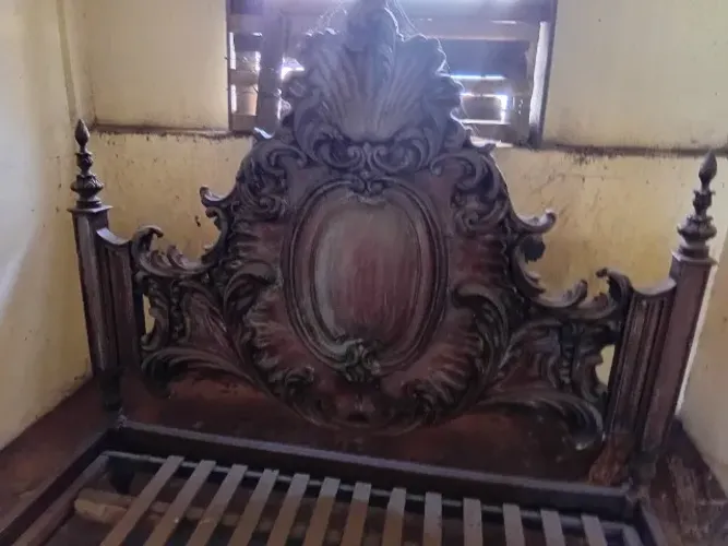 Cama antiga com cabeceira entalhada a mão