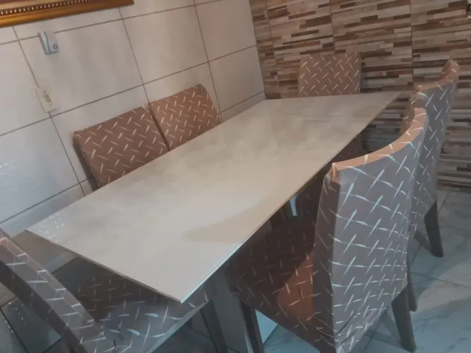 Mesa de 6 cadeiras com tampa de vidro.