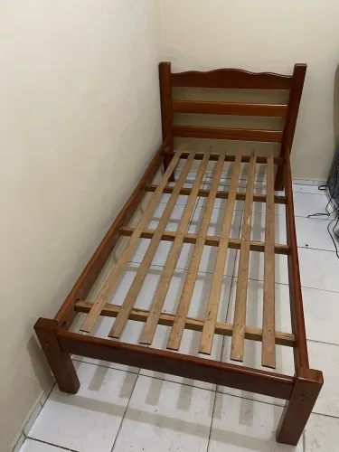 Cama de solteiro de madeira envernizada.