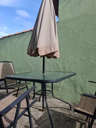 Conjunto mesa com quatro cadeiras e guarda-sol área externa