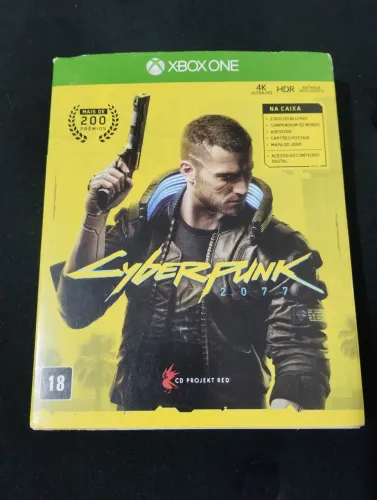 Jogo Cyberpunk 2077, com encartes, mapa físico e cartão postal do jogo.