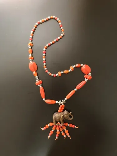 Colar longo laranja com pingente de elefante e franjas de contas.