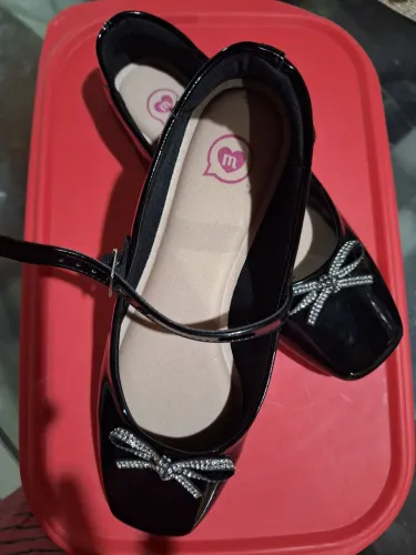 Sapato em verniz preto com laços prata.
