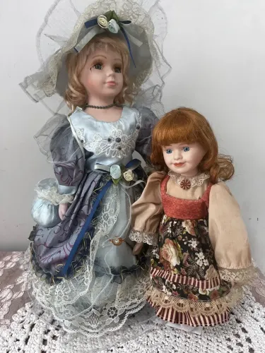 Duas bonecas d e porcelana antigas uma dama vitoriana e uma camponesa.