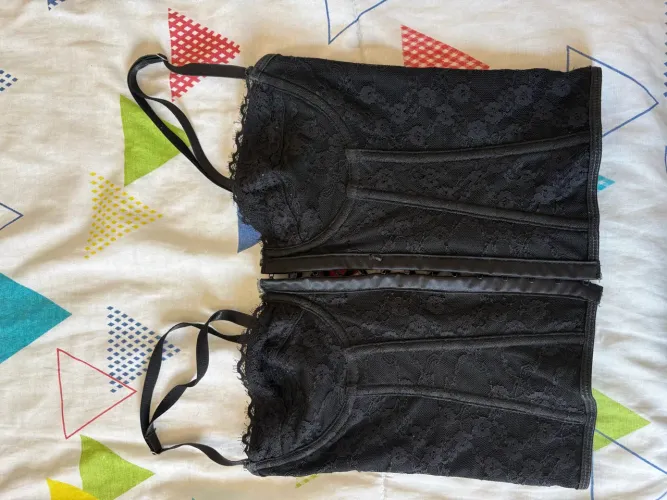 Corset preto, todo de renda, fecho frontal e decote cruzado nas costas.