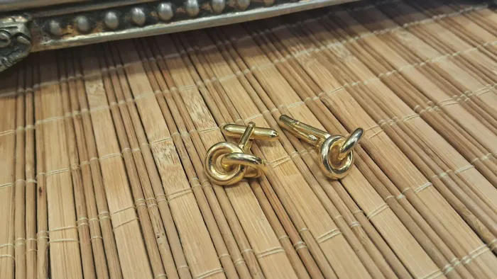 Antigas abotoaduras masculinas douradas, com um design de nó clássico.