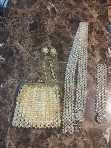 Conjunto de acessórios de cristal, bolsa, colar, pulseira e brincos.