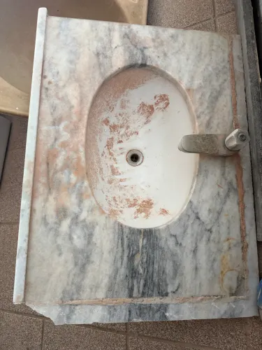 Bancada em mármore natural para banheiro, acompanhando cuba embutida e torneira metálica.