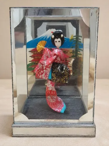 Boneca gueixa japonesa em vitrine de vidro espelhado 