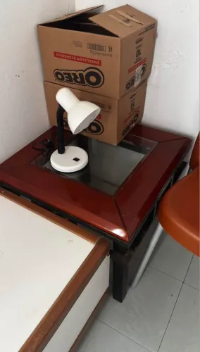Vendo pequena escrivaninha de vidro no meio, com um abajur. 